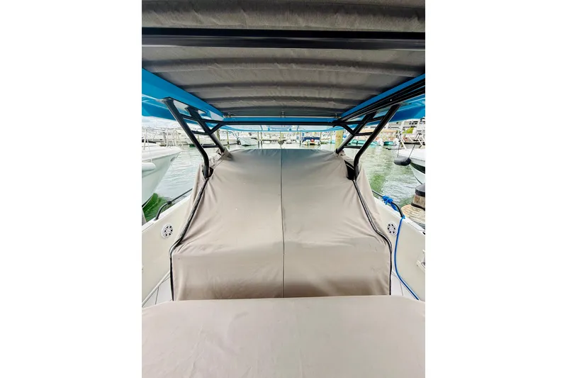 Slide: The Image of 2023 Axopar 37 Sun Top boat with covered seating area at a marina. - 64