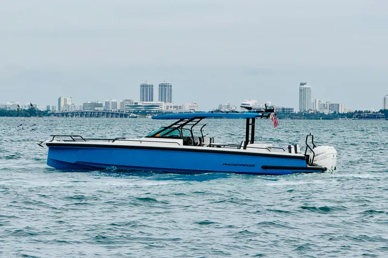 Slide: The Image of 2021 Axopar 37 Sun Top boat cruising on water with city skyline backdrop. - 9