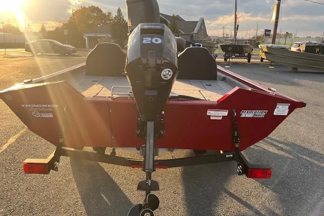 Slide: The Image of 2025 Tracker Pro Team 175 boat with 20 HP motor in a parking lot at sunset. - 14
