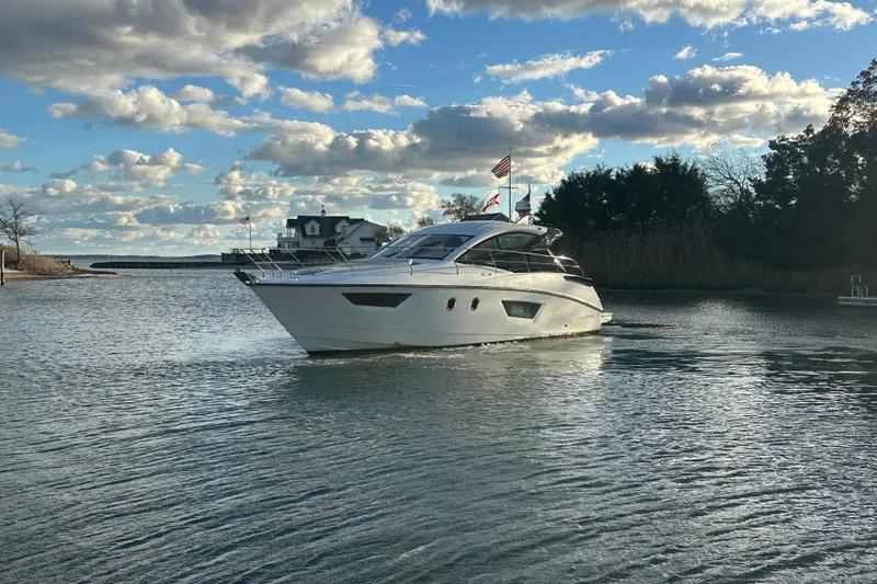 Slide: The Image of 2019 Beneteau Gran Turismo 40 yacht cruising on a serene waterway under a partly cloudy sky. - 2
