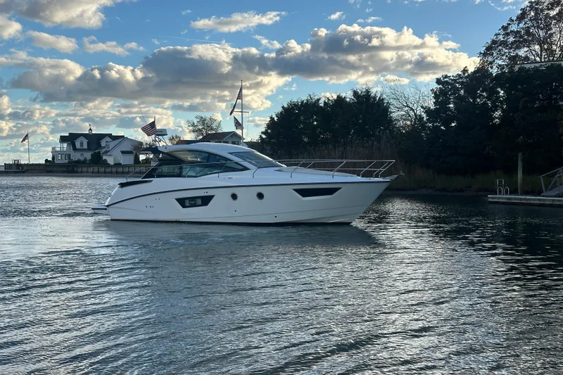 Slide: The Image of 2019 Beneteau Gran Turismo 40 yacht cruising on a serene waterway under a partly cloudy sky. - 4