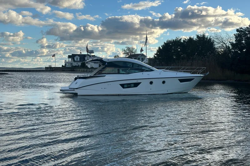 Slide: The Image of 2019 Beneteau Gran Turismo 40 yacht cruising on a serene waterway under a cloudy sky. - 5