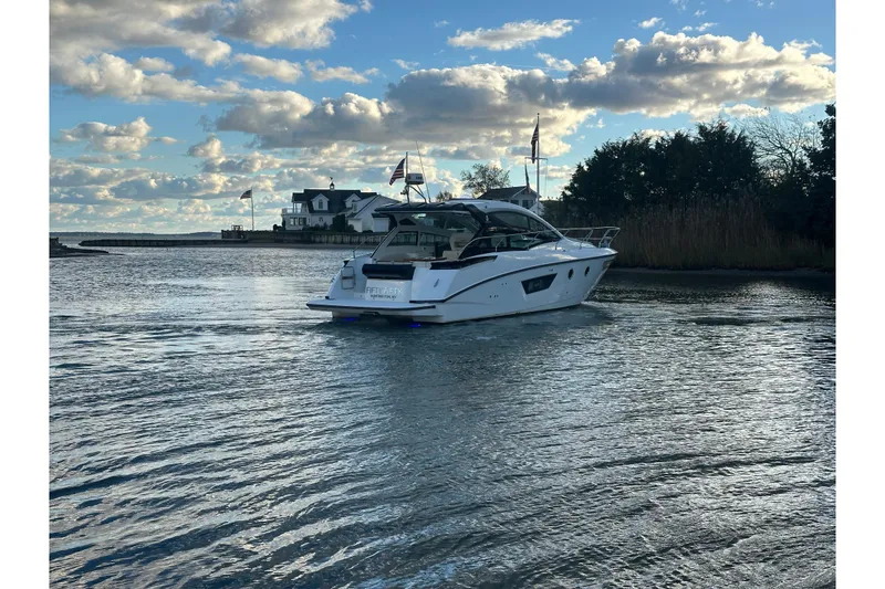Slide: The Image of 2019 Beneteau Gran Turismo 40 yacht cruising on a serene waterway under a partly cloudy sky. - 6