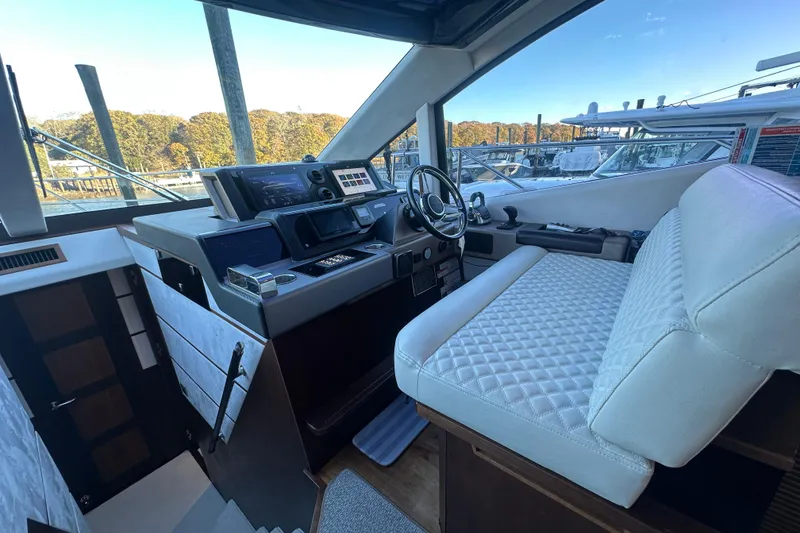 Slide: The Image of Helm of 2017 Galeon 560 Sky yacht with modern controls and white seating. - 13