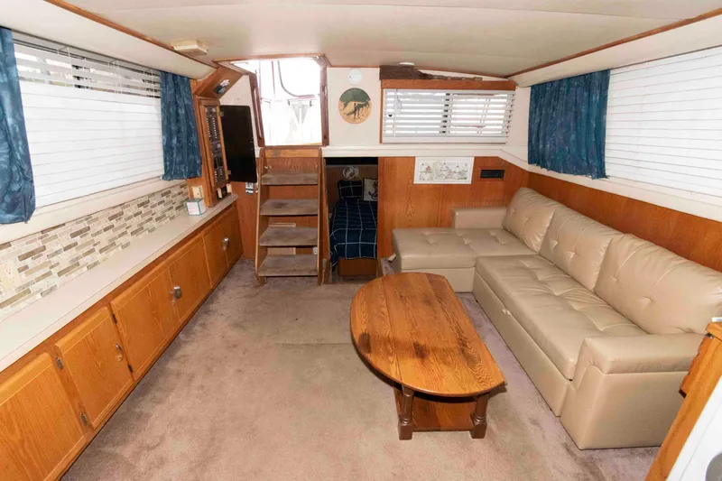 Slide: The Image of 1990 Silverton 40 Aft Cabin interior with beige sofa, wooden table, and carpeted floor. - 14