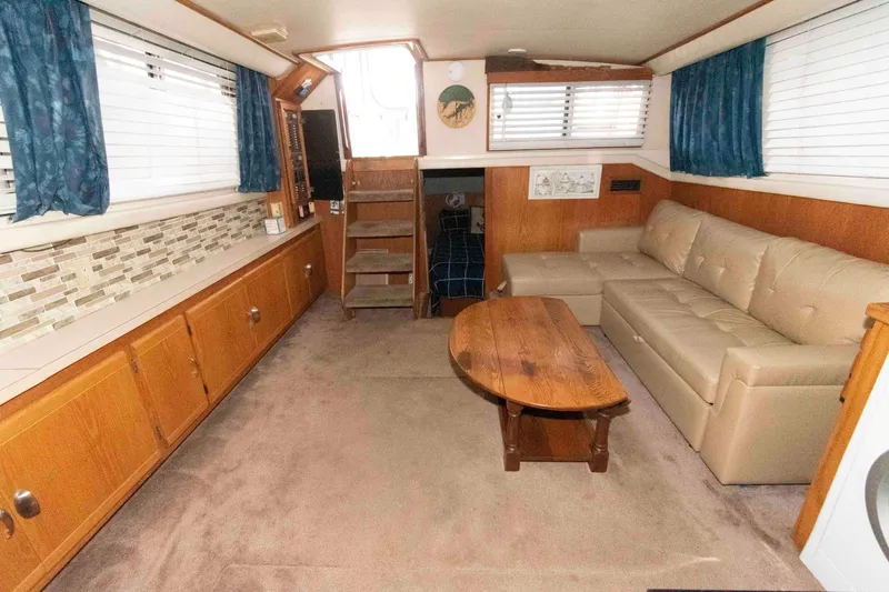 Slide: The Image of 1990 Silverton 40 Aft Cabin interior with beige sofa, wooden table, and blue curtains. - 15