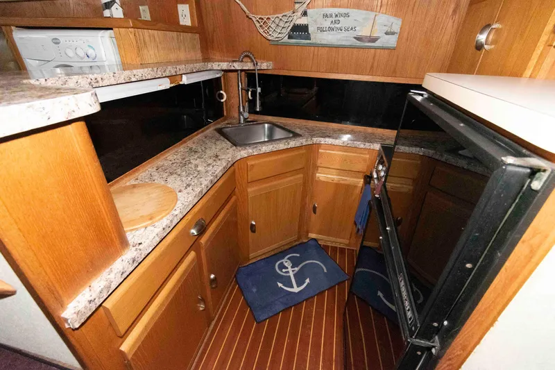 Slide: The Image of 1990 Silverton 40 Aft Cabin kitchen with wood cabinetry, granite countertops, and nautical decor. - 16