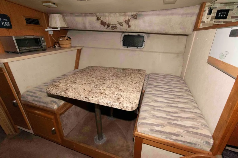 Slide: The Image of 1990 Silverton 40 Aft Cabin interior with dining area, featuring a granite-style table and cushioned seating. - 17