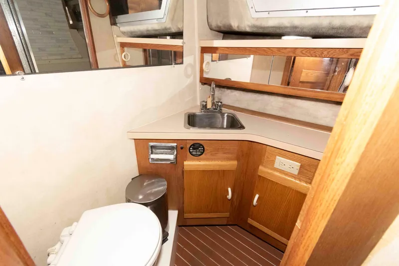 Slide: The Image of 1990 Silverton 40 Aft Cabin bathroom with sink, toilet, and wooden cabinetry. - 20