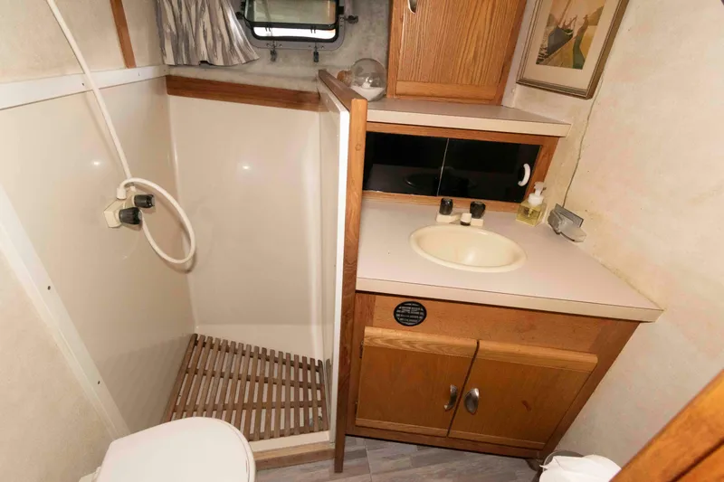 Slide: The Image of 1990 Silverton 40 Aft Cabin bathroom with shower, sink, and wooden cabinetry. - 22