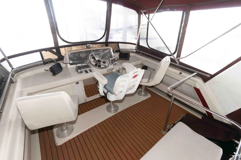 Slide: The Image of 1990 Silverton 40 Aft Cabin helm with steering wheel and seating, featuring wood-style flooring. - 6