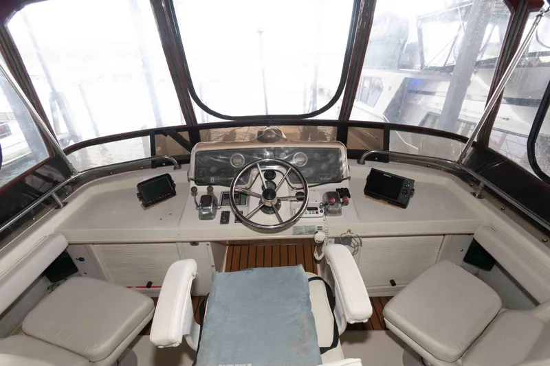 Slide: The Image of 1990 Silverton 40 Aft Cabin helm with steering wheel, navigation equipment, and seating. - 7