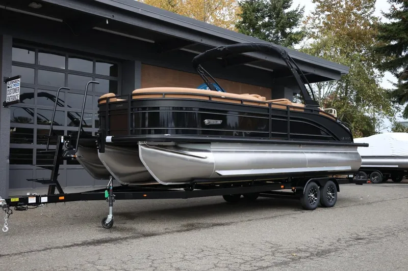 Slide: The Image of 2026 Harris Solstice 250 SL pontoon boat on trailer, parked outside a building. - 12