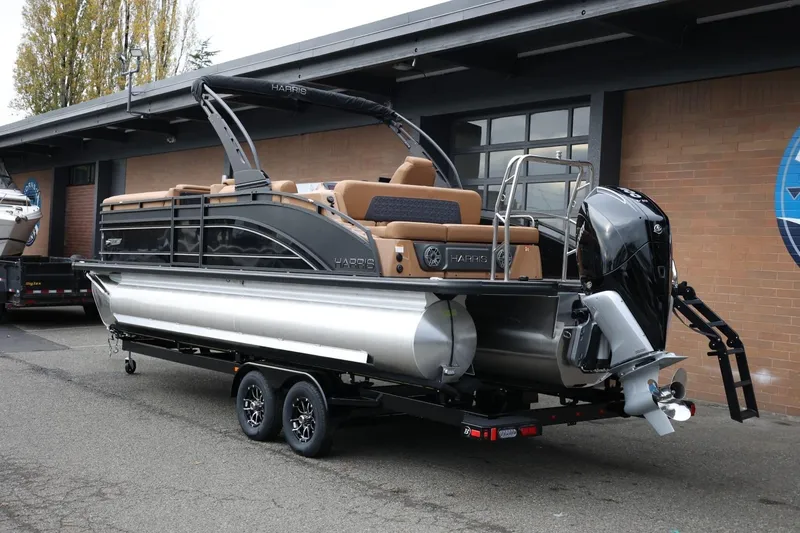Slide: The Image of 2026 Harris Solstice 250 SL pontoon boat on trailer, parked outside a building. - 3