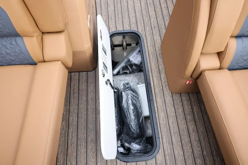 Slide: The Image of 2026 Harris Solstice 250 SL boat interior storage compartment with tan and gray seating. - 41
