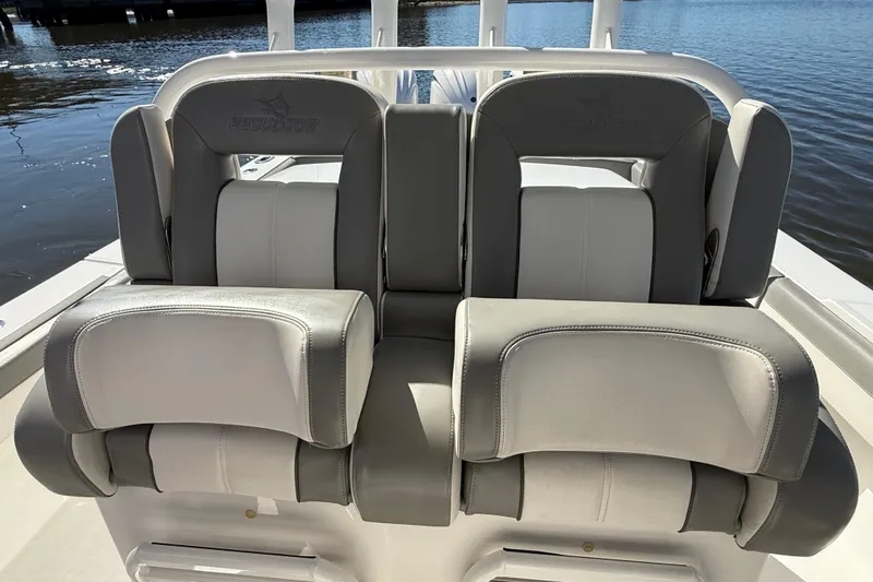 Slide: The Image of 2022 Regulator 34 boat seats with gray and white upholstery, docked by the water. - 19