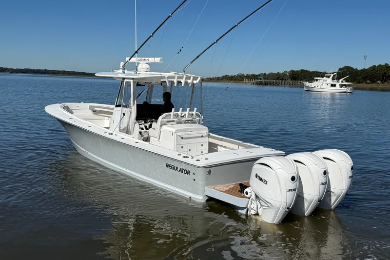 Slide: The Image of 2022 Regulator 34 boat with triple Yamaha engines on calm water. - 2