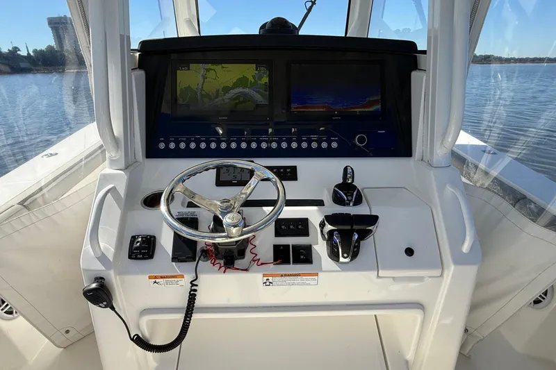 Slide: The Image of 2022 Regulator 34 boat helm with dual screens and steering wheel on calm water. - 7