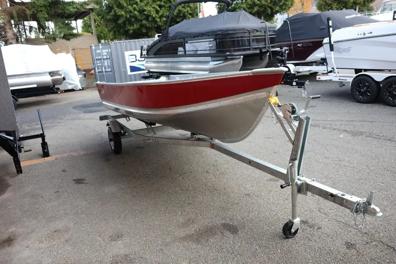 Slide: The Image of 2026 Lund SSV-16 Tiller boat on trailer, red and silver, parked outdoors. - 10