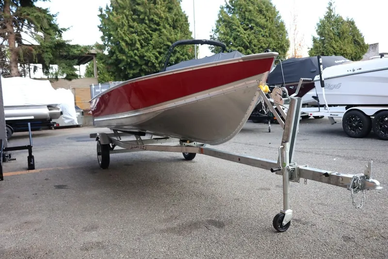 Slide: The Image of 2026 Lund SSV-16 Tiller boat on trailer, red and silver, parked outdoors. - 11