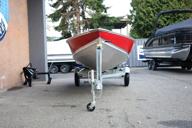 Slide: The Image of 2026 Lund SSV-16 Tiller boat on trailer, parked outdoors near other boats. - 13