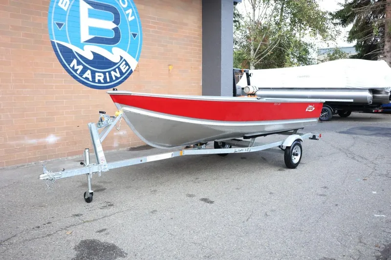 Slide: The Image of 2026 Lund SSV-16 Tiller boat on trailer, red and silver, parked outside dealership. - 14