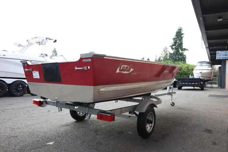 Slide: The Image of 2026 Lund SSV-16 Tiller boat on trailer, parked outdoors near other boats. - 9