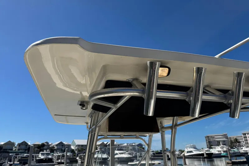 Slide: The Image of 2006 Boston Whaler 320 Outrage boat with rod holders, marina background, clear blue sky. - 28