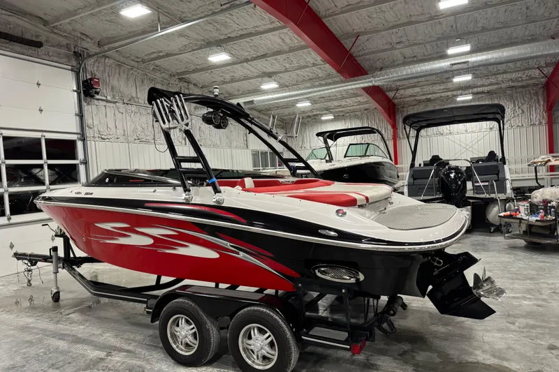 Slide: The Image of 2011 Four Winns 210 Horizon SS boat in a garage, featuring a sleek red and white design. - 4