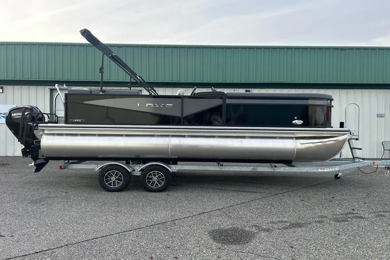 The Image of 2026 Lowe LS 210 WT pontoon boat on trailer, parked outside a building. - 1