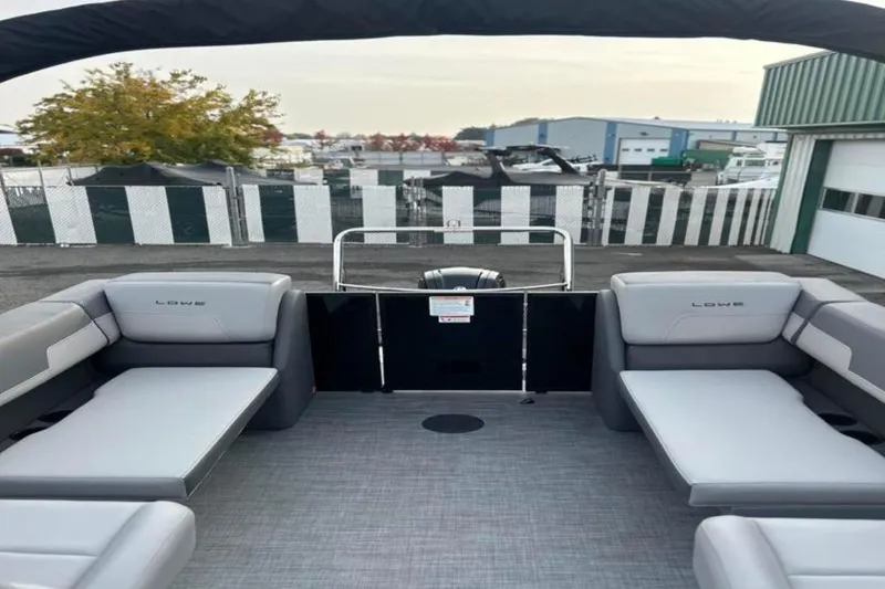 Slide: The Image of 2026 Lowe LS 210 WT pontoon boat interior with gray seating and marina background. - 26