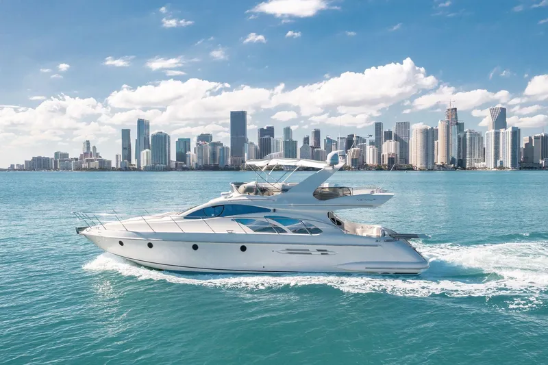 The Image of 2006 Azimut 50 Fly yacht cruising near a city skyline under a clear blue sky. - 0