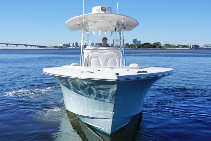 Slide: The Image of 2018 Regulator 28 boat cruising on calm water with cityscape in background. - 8