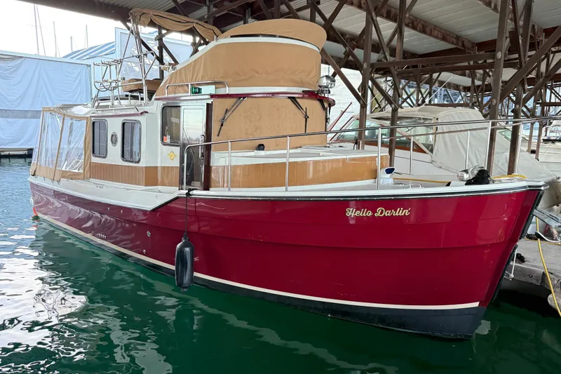 The Image of 2016 Ranger Tugs R-31 CB boat docked in marina, featuring red hull and tan canopy. - 0