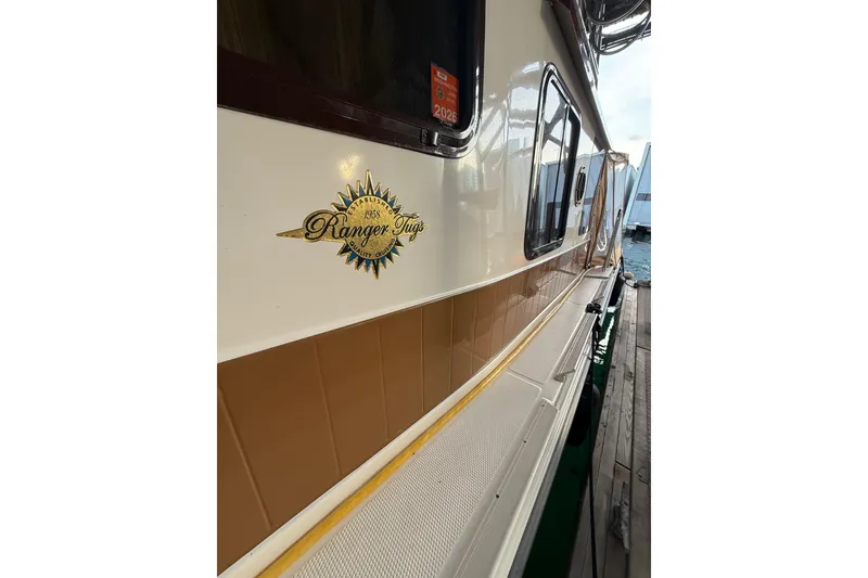 Slide: The Image of 2016 Ranger Tugs R-31 CB boat side view with logo and dock background. - 10