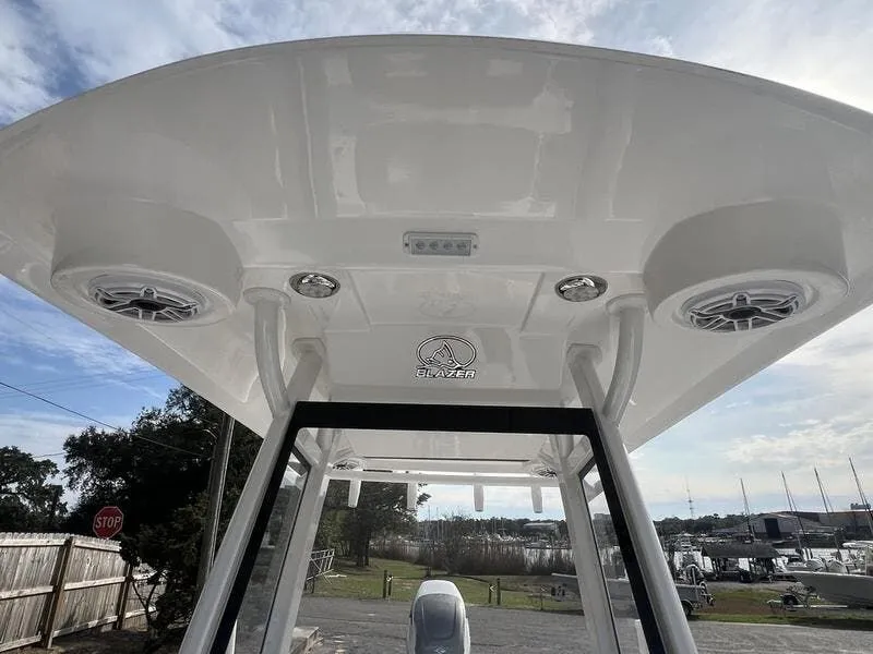 Slide: The Image of 2024 Blazer GTS 2550 BAY boat with speakers and canopy, marina background. - 10
