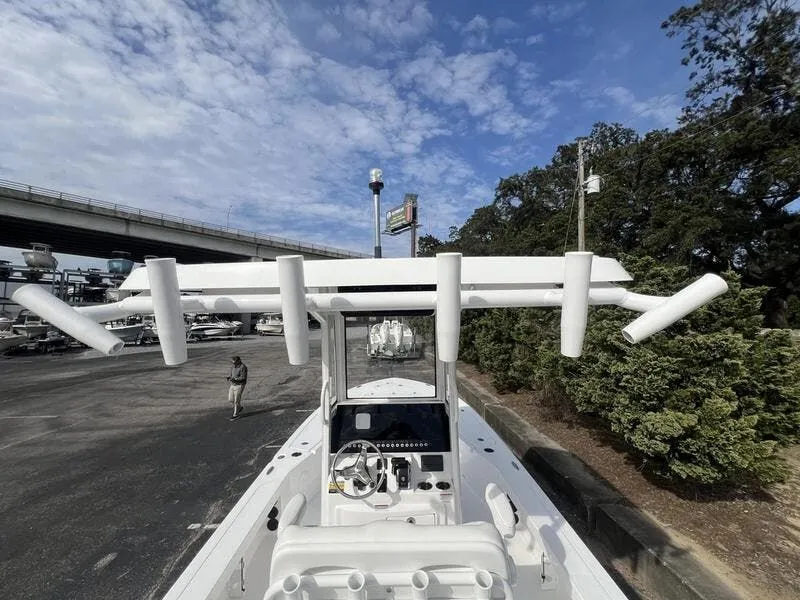 Slide: The Image of 2024 Blazer GTS 2550 BAY boat with T-top and rod holders, parked under a cloudy sky. - 3