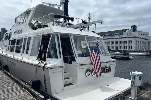 Slide: The Image of 1999 Pacific Mariner 65 Motoryacht docked, displaying American flag, overcast sky. - 10