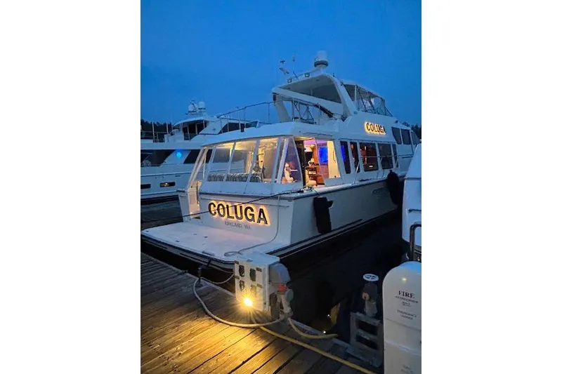 Slide: The Image of 1999 Pacific Mariner 65 Motoryacht docked at night, illuminated name "COLUGA." - 11