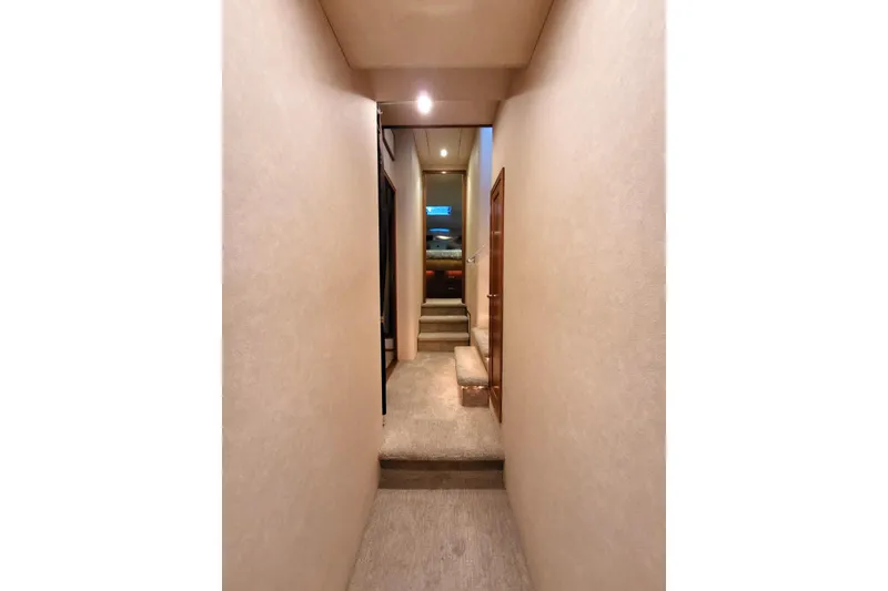 Slide: The Image of Narrow hallway inside 1999 Pacific Mariner 65 Motoryacht, featuring carpeted steps and soft lighting. - 54