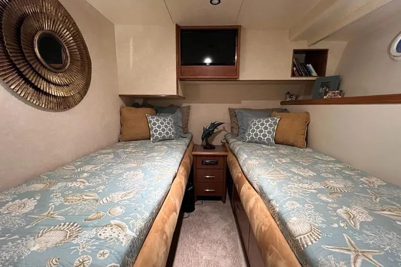 Slide: The Image of 1999 Pacific Mariner 65 Motoryacht cabin with twin beds, decorative pillows, and wall art. - 63