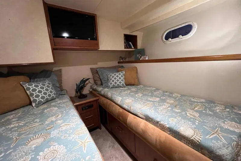Slide: The Image of 1999 Pacific Mariner 65 Motoryacht cabin with twin beds, nautical decor, and a wall-mounted TV. - 64