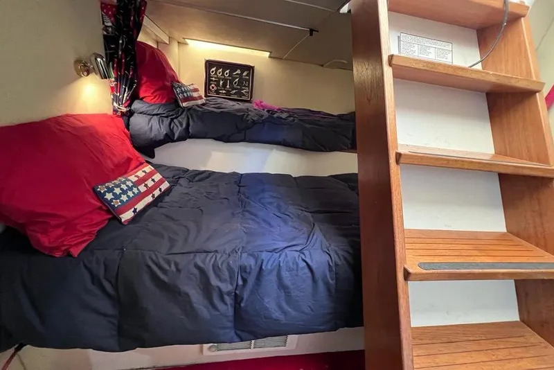 Slide: The Image of Cozy bunk beds with red and blue bedding in a 1999 Pacific Mariner 65 Motoryacht cabin. - 69