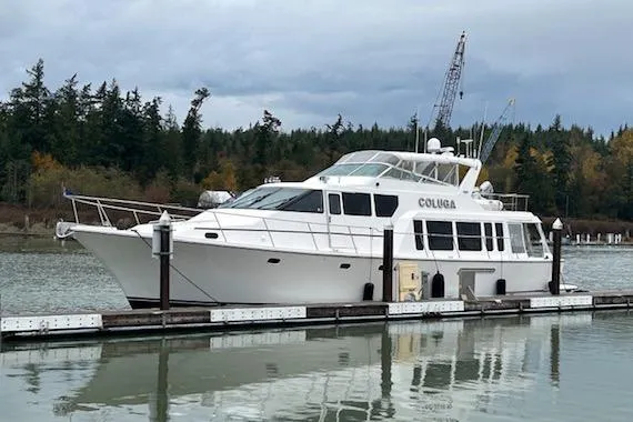 Slide: The Image of 1999 Pacific Mariner 65 Motoryacht docked on calm water with forested background. - 8