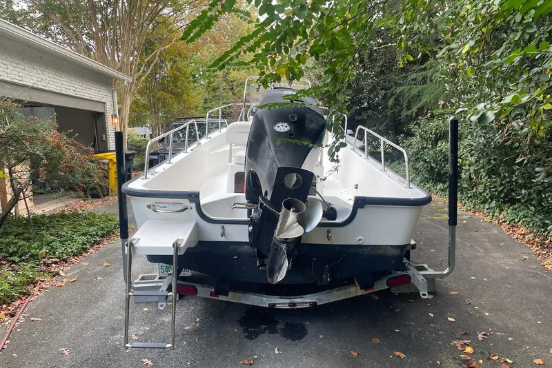 Slide: The Image of 2008 Boston Whaler 170 Montauk boat on trailer, parked in driveway surrounded by greenery. - 2