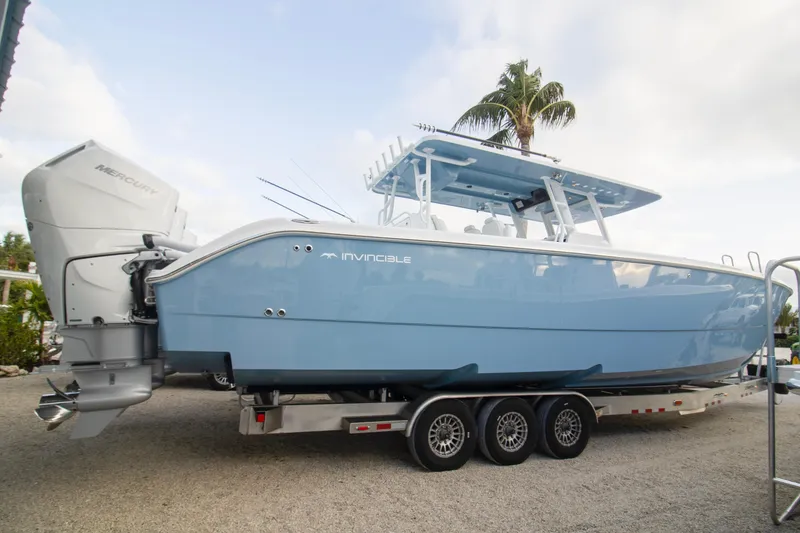 The Image of 2026 Invincible 38 Catamaran in light blue on a trailer, featuring twin Mercury engines. - 0