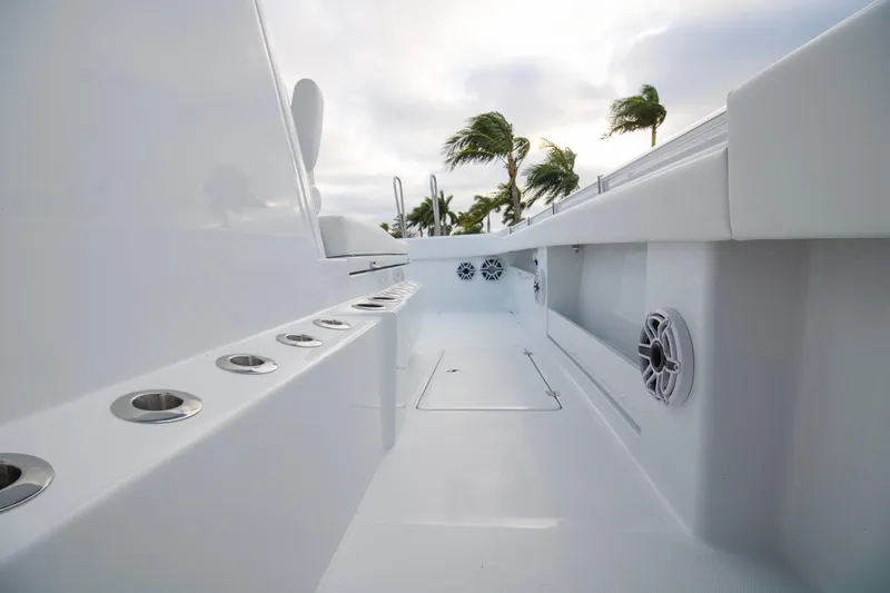 Slide: The Image of 2026 Invincible 38 Catamaran deck with rod holders and speakers, palm trees in background. - 12