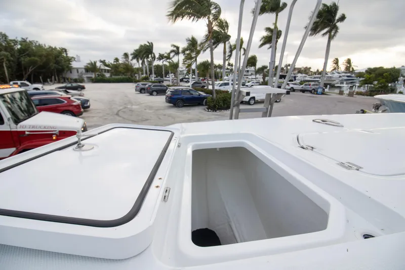 Slide: The Image of 2026 Invincible 38 Catamaran with open storage compartment, parked near marina with palm trees. - 13