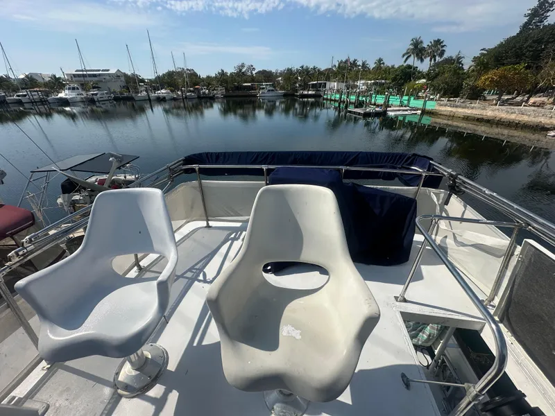 Slide: The Image of 1974 Bertram 42 Motor Yacht deck with chairs, overlooking marina and palm trees. - 17