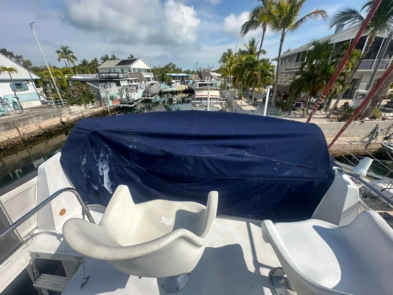 Slide: The Image of 1974 Bertram 42 Motor Yacht deck with covered seating, docked near palm trees and waterfront homes. - 20